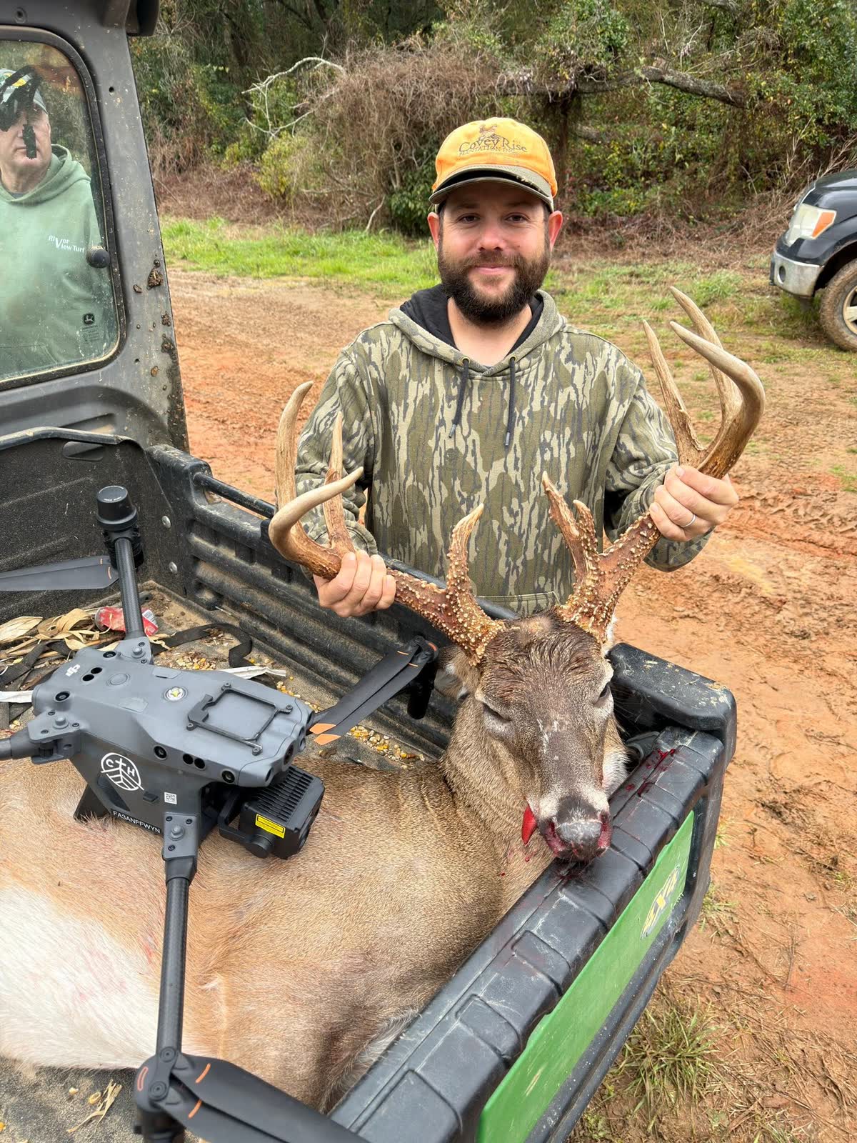 A hunter standing in the bed of a UTV lifting the heavy rack of the recovered buck