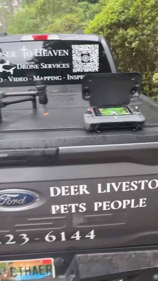 The drone and its controller loaded in the bed of the Closer to Heaven truck, tailgate lettered Deer, Livestock, Pets, People